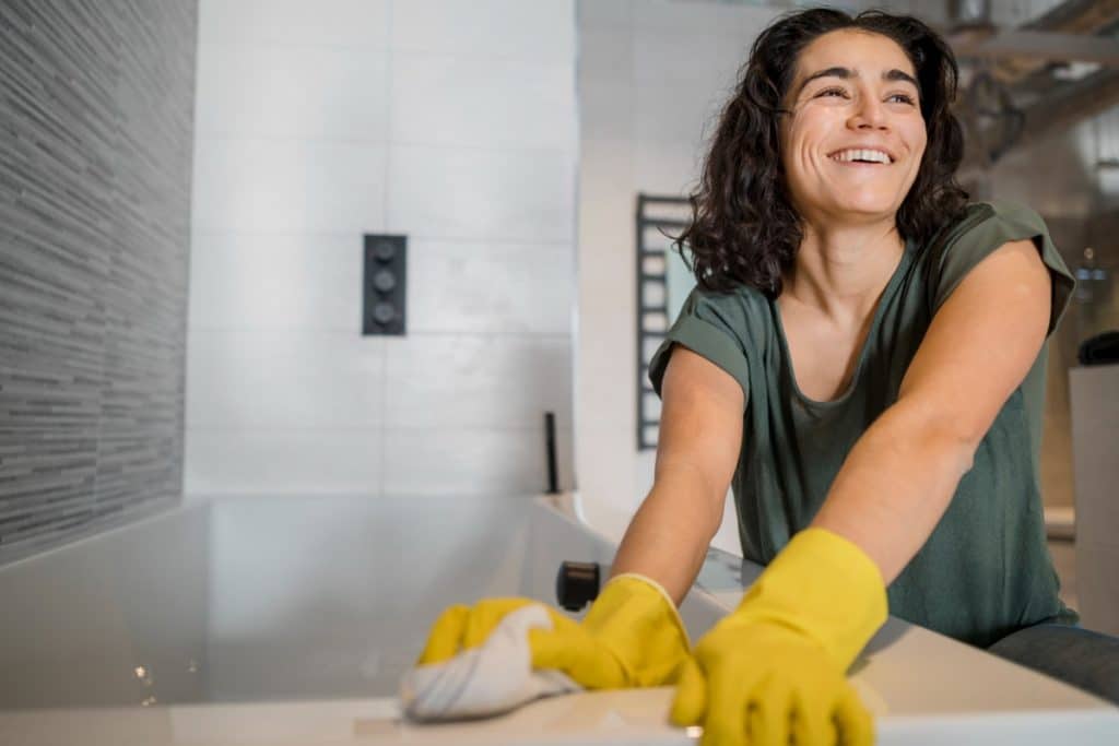 Une jeune femme portant des gants et nettoyant un comptoir.