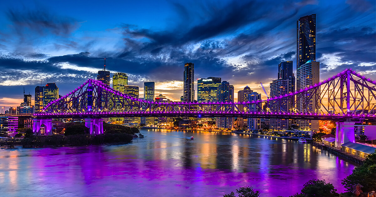 Le Story Bridge s'allume en violet avec la ville de Brisbane en arrière-plan au crépuscule