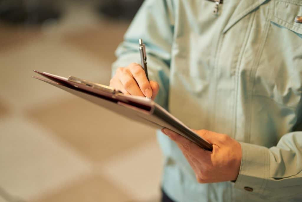 Un homme tenant un presse-papiers d'inspection et écrivant des notes.