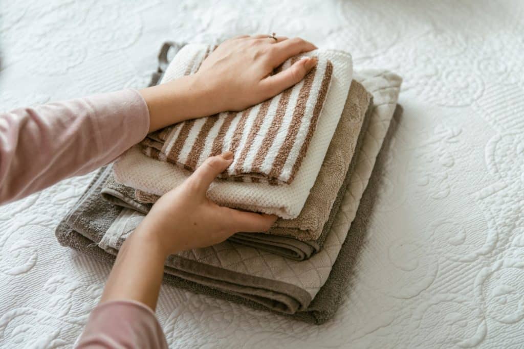 On voit les mains d'une femme plier une pile de serviettes.